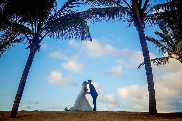 Silhoutte of bride and groom kissing on a beach, Tropical palm trees.